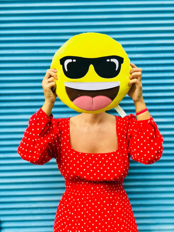 फोटो woman covering face with anthropomorphic face cushion against shutter