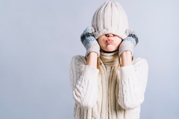 Foto donna che copre il viso con berretto e le guance che soffia