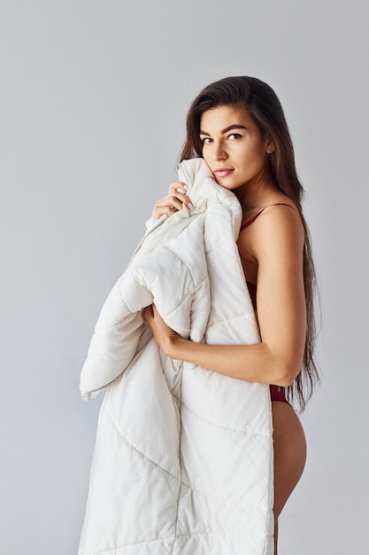 Woman covering her body by towel in the studio against white background.