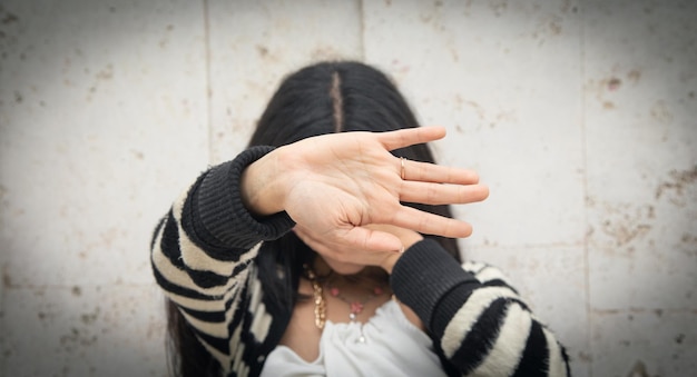 Woman covering her face and doing stop sign