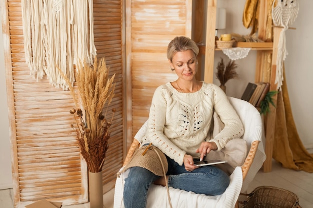 Woman in a cozy interior with knitting using a laptop for needlework Women's hobby