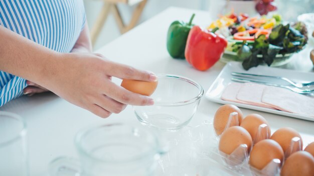 Photo woman cracking an egg into a bowl