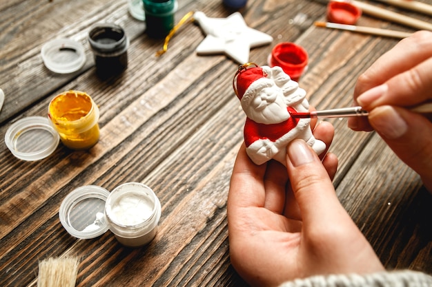 Woman create stylish christmas gifts, paints porcelain figurines.