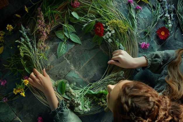 Photo woman creating flower wreath at table showcasing art with terrestrial plants