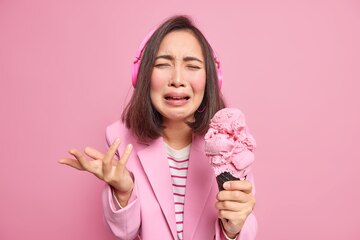 Premium Photo  Woman cries from despair has bad mood raises palm holds  delicious ice cream wears headphones listens music dressed formally cannot  afford her dessert keeps to strict diet