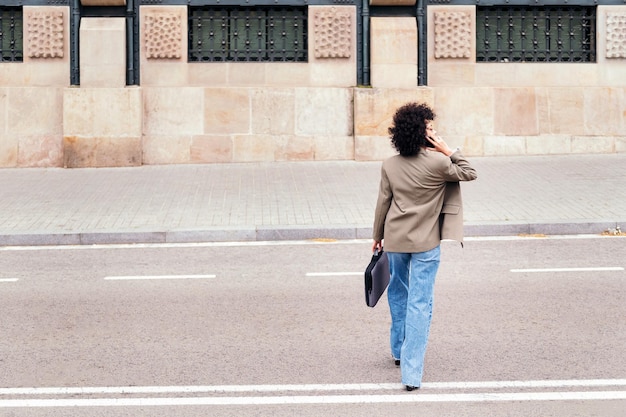 写真 携帯電話で話している通りを渡る女性