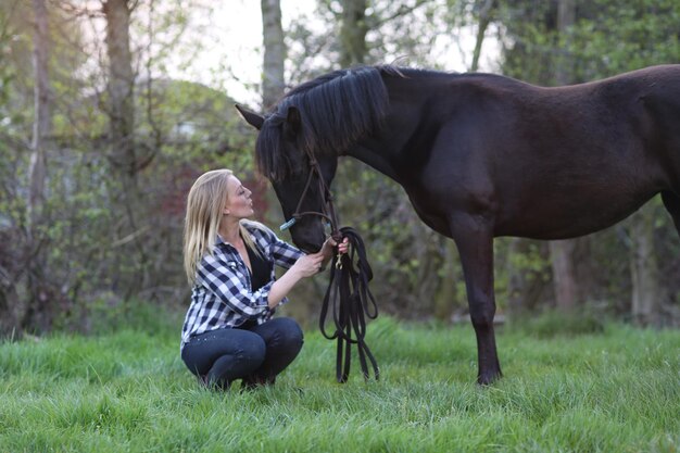 Woman crouching by horse land