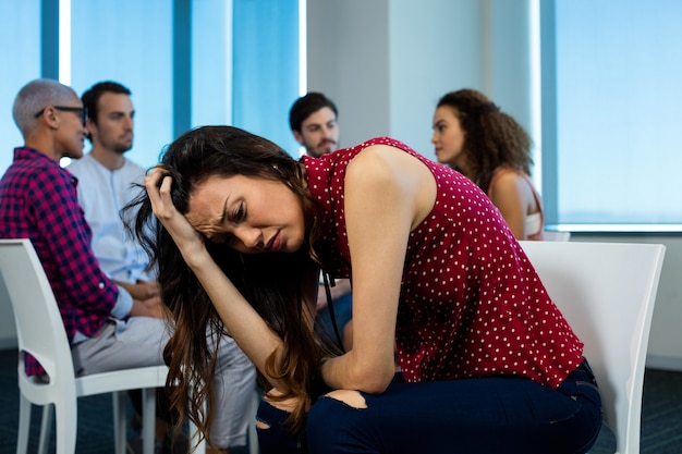 Woman crying while creative business team behind at office