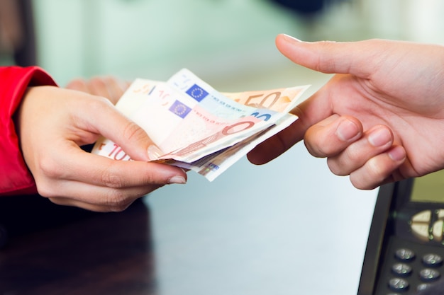 Woman customer paying with money. Hands detail. 