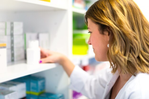 Foto cliente della donna nella farmacia che prende una scatola della medicina