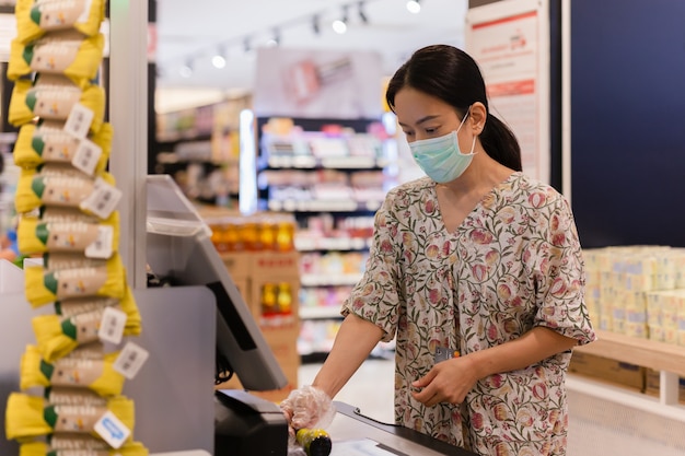 Woman customer in protective mask self service check out till and digital bar code scanner