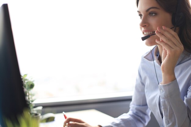 Operatore di assistenza clienti donna con auricolare e sorridente.