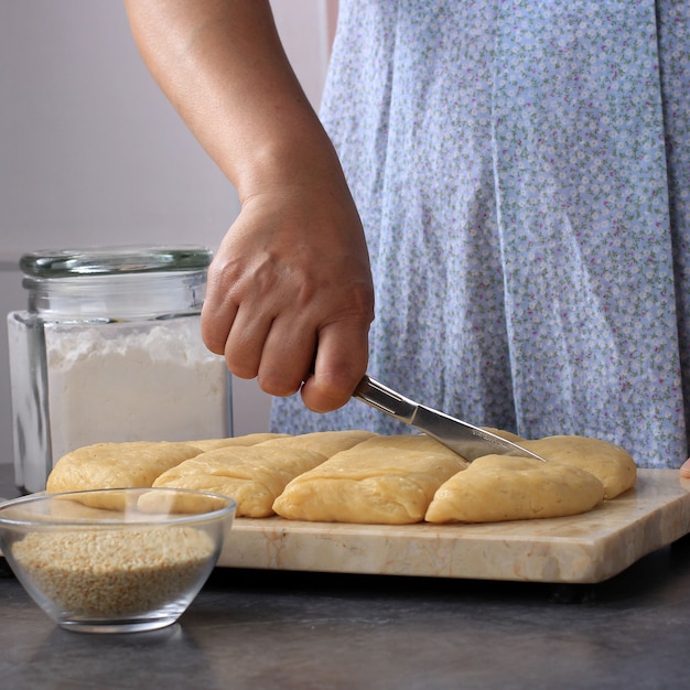 Donna tagliata pasta di pane, processo di cottura in cucina. preparare odading/roti bantal/golang galing/bolang baling, cibo di strada virale da bandung, indonesia