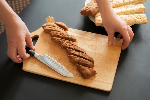 Woman cut bread with knife at the kitchen b