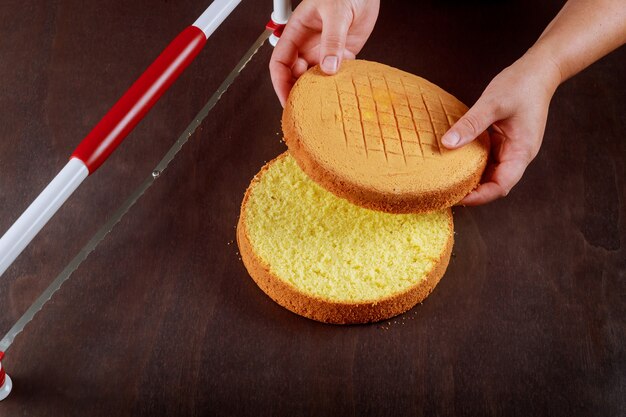 Woman cut the top of cake with a serrated leveler cake