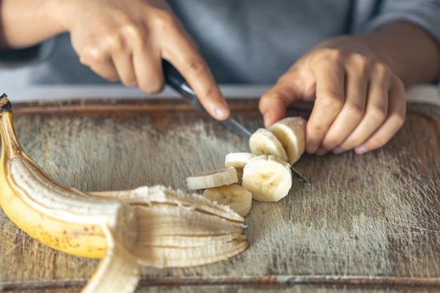 Foto una donna taglia una banana su un tagliere