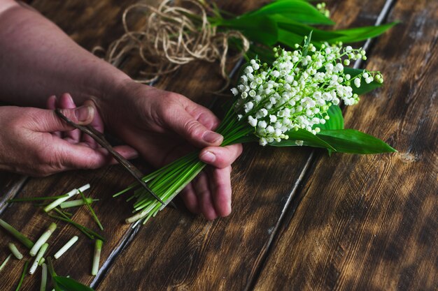 Woman cuts a bouquet of lilies of the valley.