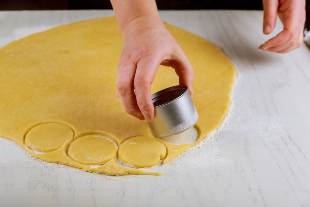 Woman cuts dough for baking cookies on table