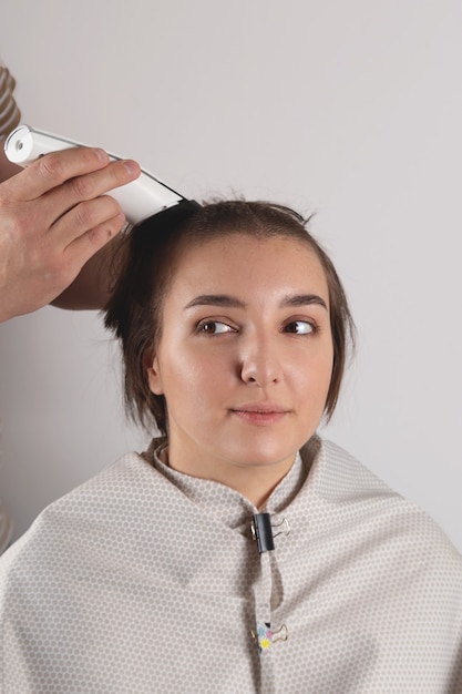 Una donna si taglia i capelli molto corti con un rasoio elettrico. stile divertente e audace