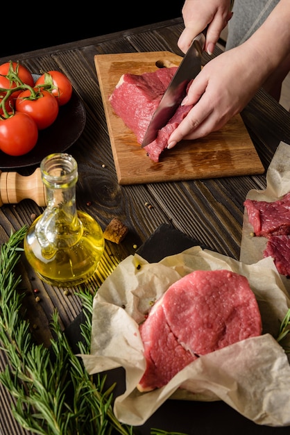 Woman cuts raw meat to cook steaks