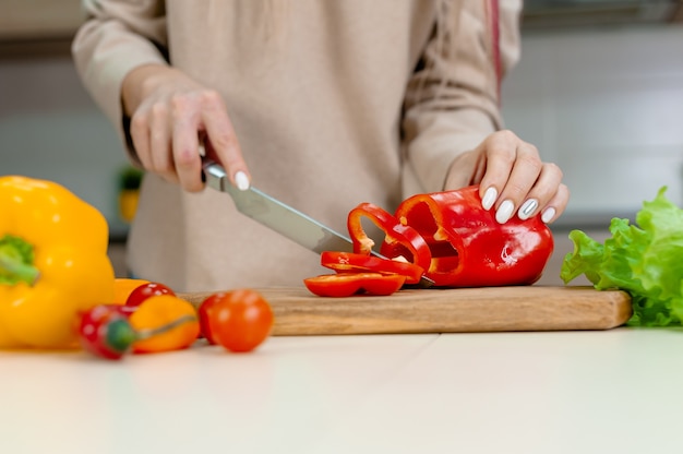 Woman cuts ripe vegetables in the kitchen.