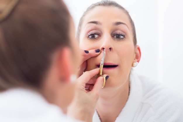 Woman cutting her nostril hair