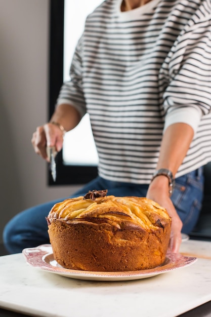 Woman cutting homemade apple pie at the kitchen