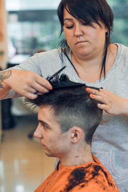 Woman cutting man hair in salon