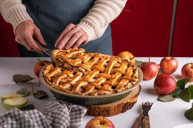 Женщина режет кусочек вкусного яблочного пирога на тарелке, готовую к еде