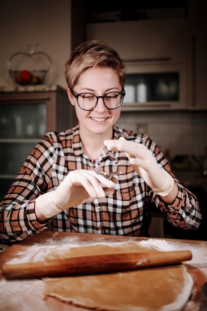 Donna che taglia un po 'di pasta di pan di zenzero con un cookie cutter in metallo