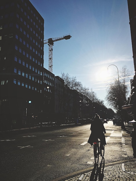 Foto donna in bicicletta per strada davanti agli edifici contro il cielo