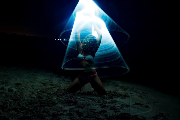 Photo woman dancing in cone of light on sand