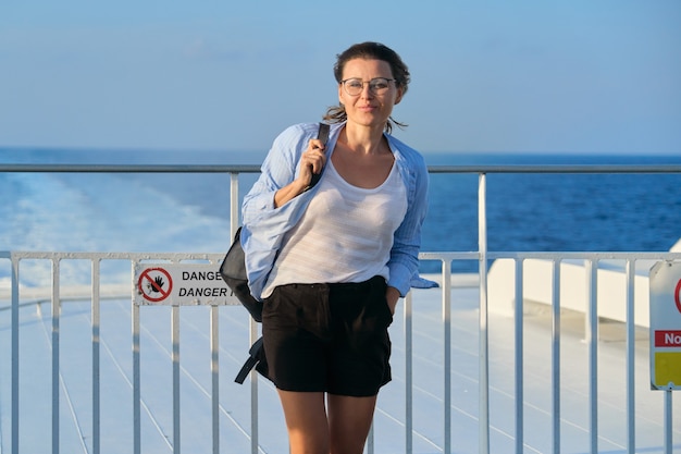 Woman on deck of ferry, female standing in strong wind, enjoying sea travel, sunset at sea, copy space