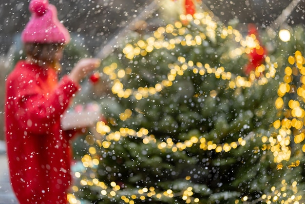 Woman decorates christmas tree at bacyard blurred image