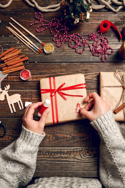 Женщина украшает коробку рождественскими подарками