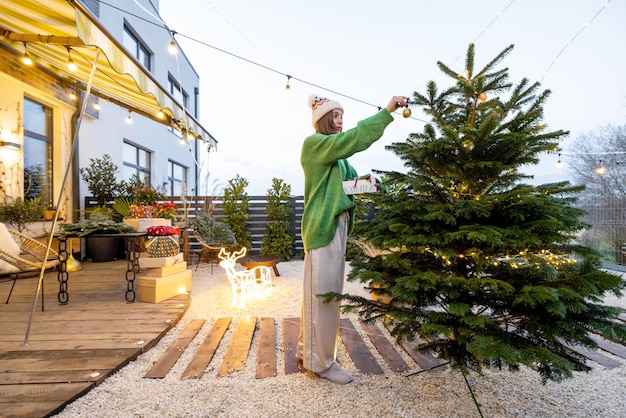 Woman decorating christmas tree at backyard