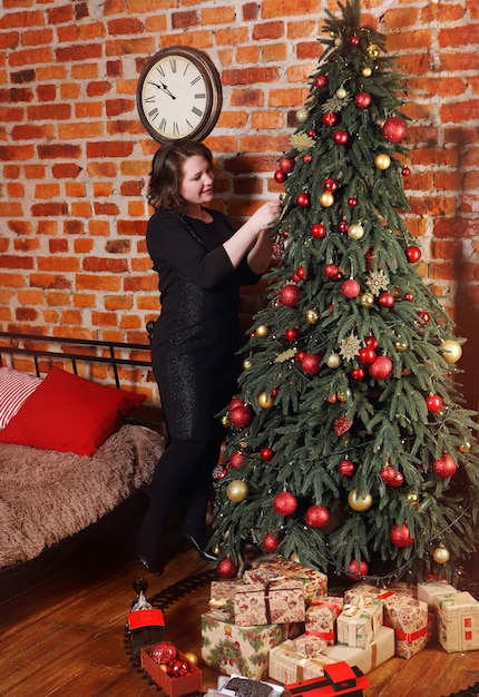 Woman decorating Christmas tree at home