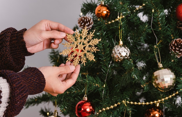 クリスマスの日に飾りでクリスマスツリーを飾る女性。