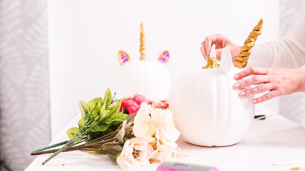 Woman decorating craft pumpkin with unicorn theme for Halloween.