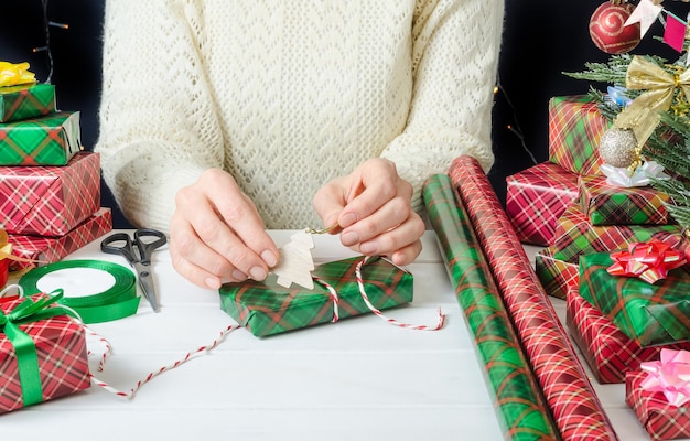 Foto donna che decora con un giocattolo di legno preparazione del regalo avvolto di natale per la vacanza