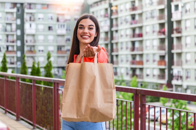 紙袋に食べ物を提供する女性。宅配フードサービス。宅配便は、名前のないバッグ付きの食品を注文しました。