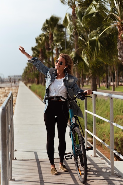 Woman in a denim jacket enjoys a solo bike ride along a seaside promenade