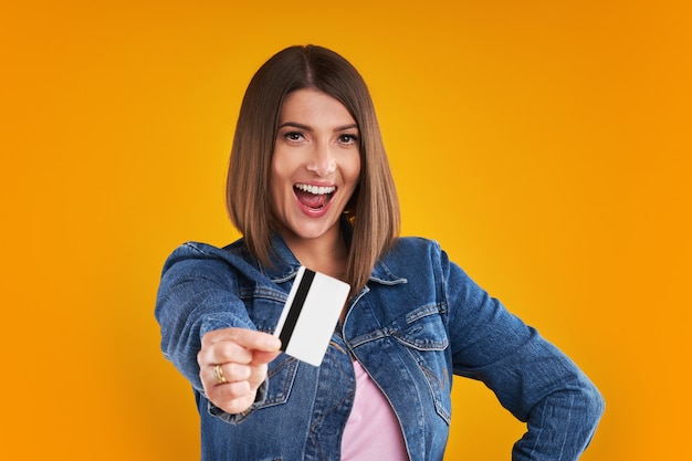 woman in denim jacket with shopping bags over yellow background