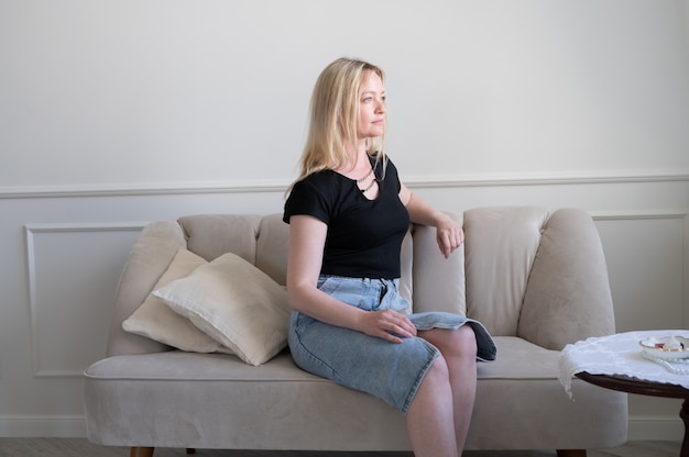 Woman in denim skirt sitting on the couch.