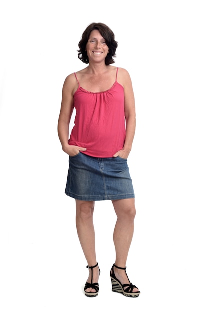 Woman in a denim skirt on white wall with hands on pocket