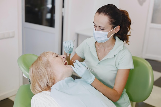 A woman in a dental chair with a dentist in a mask and gloves.