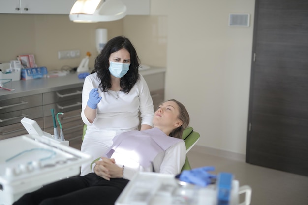 A woman in a dental chair with a patient in a dental chair