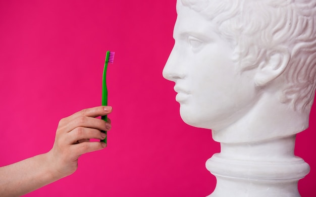 Woman dentist brushing teeth of an antique statue using a large toothbrush