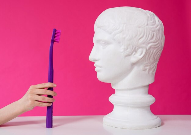 Woman dentist brushing teeth of an antique statue using a large toothbrush