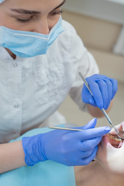 Woman dentist checking her patient for caries Redhaired woman examined by a doctor The girl will do the health of the teeth Closeup